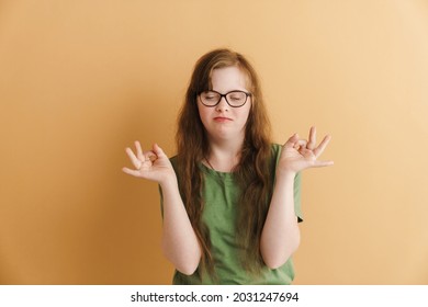 Young Calm Casual Woman With Down Syndrome Standing Over Beige Background Meditating With Eyes Shut