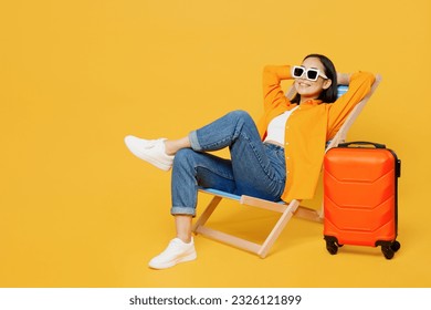 Young calm woman wear summer clothes sit in deckchair hold hands behind neck isolated on plain yellow background. Tourist travel abroad in free spare time rest getaway. Air flight trip journey concept - Shutterstock ID 2326121899