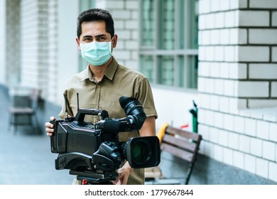 Young Cameraman Using A Professional Camcorder Outdoor Filming News While Wearing Mask Prevent Covid-19 Or Coronavirus Quarantine Pandemic.