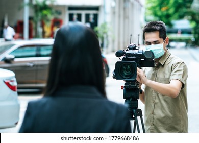 Young Cameraman Using A Professional Camcorder Outdoor Filming News While Wearing Mask Prevent Covid-19 Or Coronavirus Quarantine Pandemic.