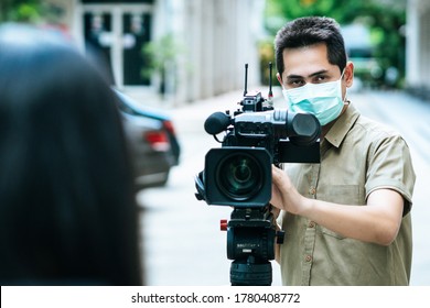 Young Cameraman Using A Professional Camcorder Outdoor Filming News While Wearing Mask Mask Prevent Covid-19 Or Coronavirus Quarantine Pandemic.