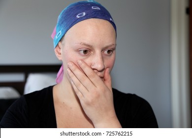 Young Cancer Patient In Headscarf Looks Shocked With Hand On Mouth