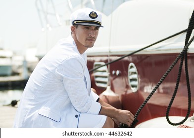 young captain looking away and holding rope of the yacht - Powered by Shutterstock