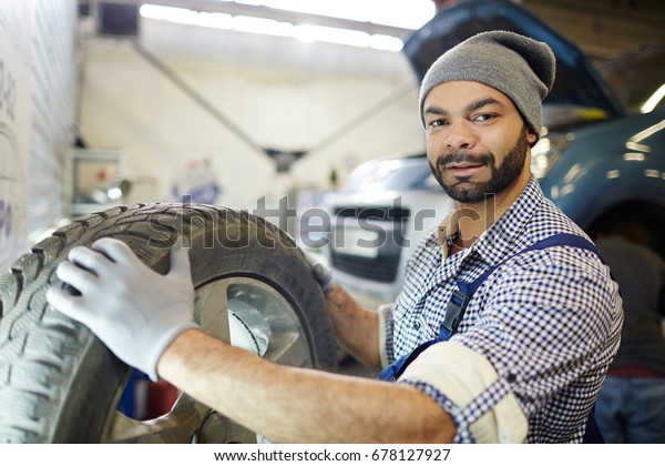 Young car repair master\
with new tire