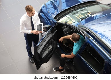 Young car salesman working with client in dealership - Shutterstock ID 1255494403