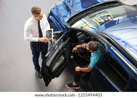 Young car salesman working with client in dealership