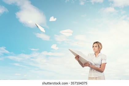 Young carefree woman with paper plane in hands - Shutterstock ID 357104375