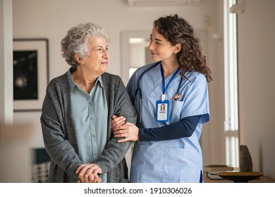 Junge Betreuerin, die älteren Frauen beim Laufen hilft. Krankenschwester hilft ihrer alten Patientin bei der Pflege zu Hause. Senior Frau mit Gehstock, die von der Krankenschwester zu Hause unterstützt wird.