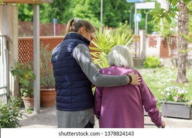 Young Carer Walking With The Elderly Woman In The Garden