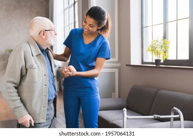 Young caring african nurse helping senior old elderly man grandfather walk . Disable old man trying to walk with the assistance aid of female doctor. - Powered by Shutterstock