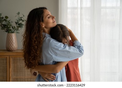 Young caring woman hugging teenage girl needing support after school troubles. Emotionless Italian mother saying goodbye to daughter standing at window at home before leaving for long business trip.  - Powered by Shutterstock