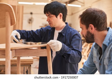 Young carpenter apprentice as cabinet maker measuring the chair with tape measure