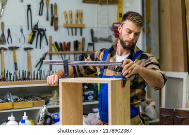 A young carpenter makes a wooden box using a clamp - Powered by Shutterstock