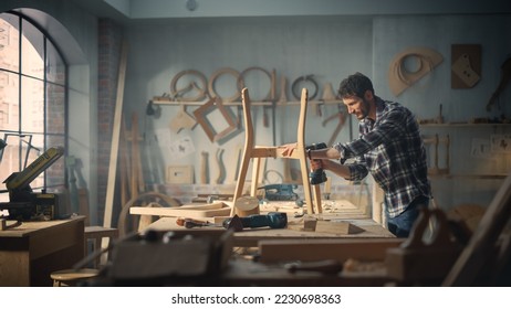 Young Carpenter Reading Blueprints and Starting to Assemble Parts of a Wooden Chair with a Rubber Hammer. Stylish Furniture Designer Working in a Studio in Loft Space with Tools on the Walls. - Shutterstock ID 2230698363