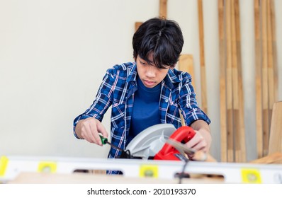 Young carpenter using a screwdriver fixing circular saw in carpentry workshop, Child learning woodworking in the craftsman workshop