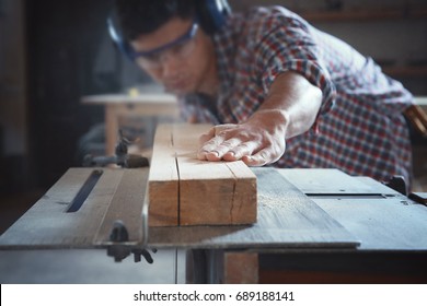 Young carpenter working with circular saw in shop