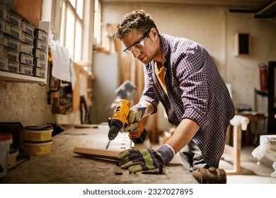 Young carpenter working in his woodworking workshop - Powered by Shutterstock