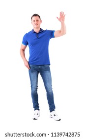 Young Casual Adult Man In Blue Polo Shirt Waving Hand And Welcoming Looking At Camera. Full Body Isolated On White Background.