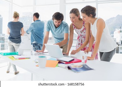 Young Casual Business People Using Laptop Together In A Bright Office