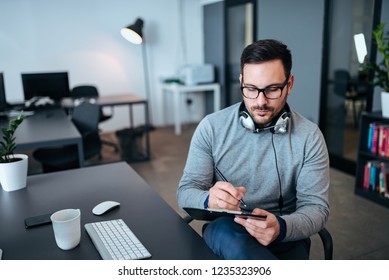 Young Casual Businessman Making Notes On Clipboard.