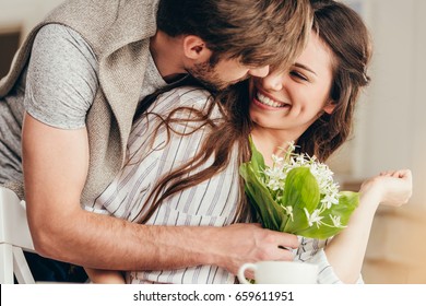 young casual couple embracing with bouquet of flowers at home - Powered by Shutterstock