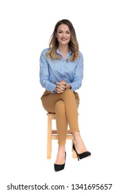 young casual dressed woman sitting on wooden chair with legs crossed and waiting for interview, full body picture