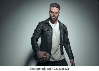 Young Casual Man Looking At The Camera With A Very Sexy And Mean Look, Holding A Rugby Ball