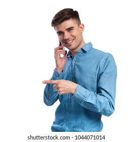 young casual man speaking on the phone is pointing finger to side on white background - Shutterstock ID 1044071014