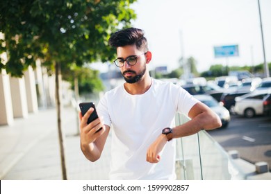 Young casual man using a smart phone texting messages in the street