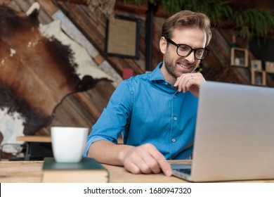 Young Casual Man Wearing Glasses Sitting At Desk Studying On Laptop Happy At The Coffeeshop