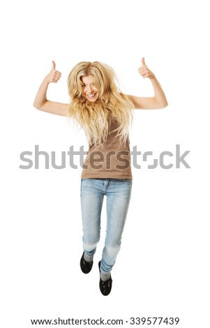 Young casual student jumping with thumbs up.