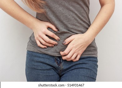 Young casual woman is having stomach ache. Woman making heart shape on her stomach. Gynecology, period, female healthcare, digestive system, Urinary Tract Infections