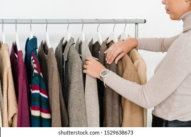 Young Casual Woman Looking Through New Seasonal Collection Of Clothes While Standing By Rack In Boutique