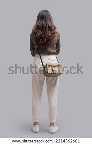 Young casual woman standing, back view, full-length portrait