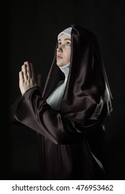 Young catholic nun with pray. Photo on black background.  