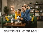 Young caucasian and adult caucasian man brothers or friends watch football and cheer match hold football ball with popcorn and beer on table at home