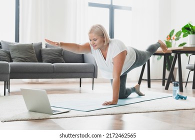 Young caucasian athlete plus size plump woman in sporty fitness clothes doing yoga training workout, shaping slimming watching online video sport tutorial at home