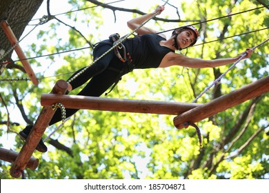 Young Caucasian Attractive Woman Climbing In Adventure Rope Park In Mountain Helmet And Safety Equipment 