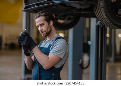 Young Caucasian Auto Mechanic Using The Drill