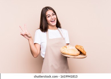 Young caucasian baker woman isolated joyful and carefree showing a peace symbol with fingers. - Shutterstock ID 1619941813