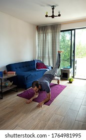 A Young Caucasian Bearded Man Doing Leg Raises Workout In His Tiny Appartment During Pandemic Lockdown.