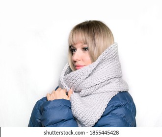 A Young Caucasian Blond Woman Looking Aside, No Mask, Holding Her Hands On The Scarf, Keeping Warm, Isolated On The White Background