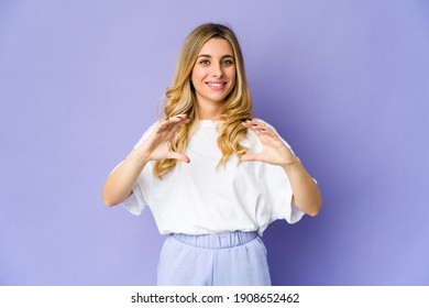 Young Caucasian Blonde Woman Holding Something With Palms, Offering To Camera.