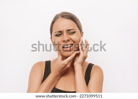 Young caucasian blonde woman suffering from jaw pain holding her chin with hands on white background. Inflammation of cervical lymph nodes, Diseases of ENT organs, facial, trigeminal nerve, toothache