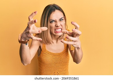 Young caucasian blonde woman wearing casual yellow t shirt shouting frustrated with rage, hands trying to strangle, yelling mad  - Shutterstock ID 2069351861