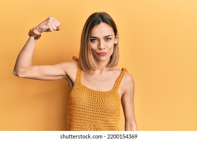 Young Caucasian Blonde Woman Wearing Casual Yellow T Shirt Strong Person Showing Arm Muscle, Confident And Proud Of Power 