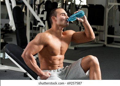 Young Caucasian Bodybuilder In The Gym, Drinking A Bottle Water