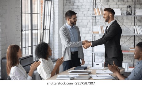 Young Caucasian boss shake hand of male employee, congratulate with job promotion at meeting, confident businessman handshake worker, greeting with employment, get acquainted at team briefing - Shutterstock ID 2359587307