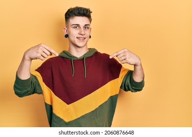 Young caucasian boy with ears dilation wearing casual sweatshirt looking confident with smile on face, pointing oneself with fingers proud and happy. 