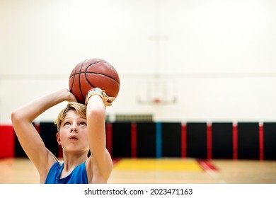 Young Caucasian Boy Playing Shooting Basketball In Stadium